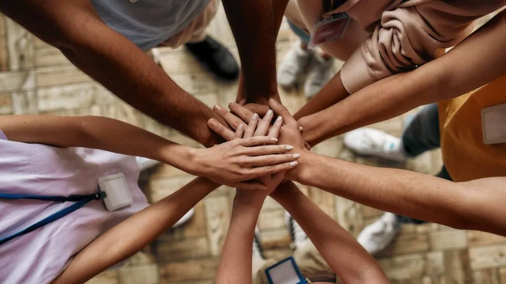 Multiple hands stacked together in a circle from above, showing unity and teamwork